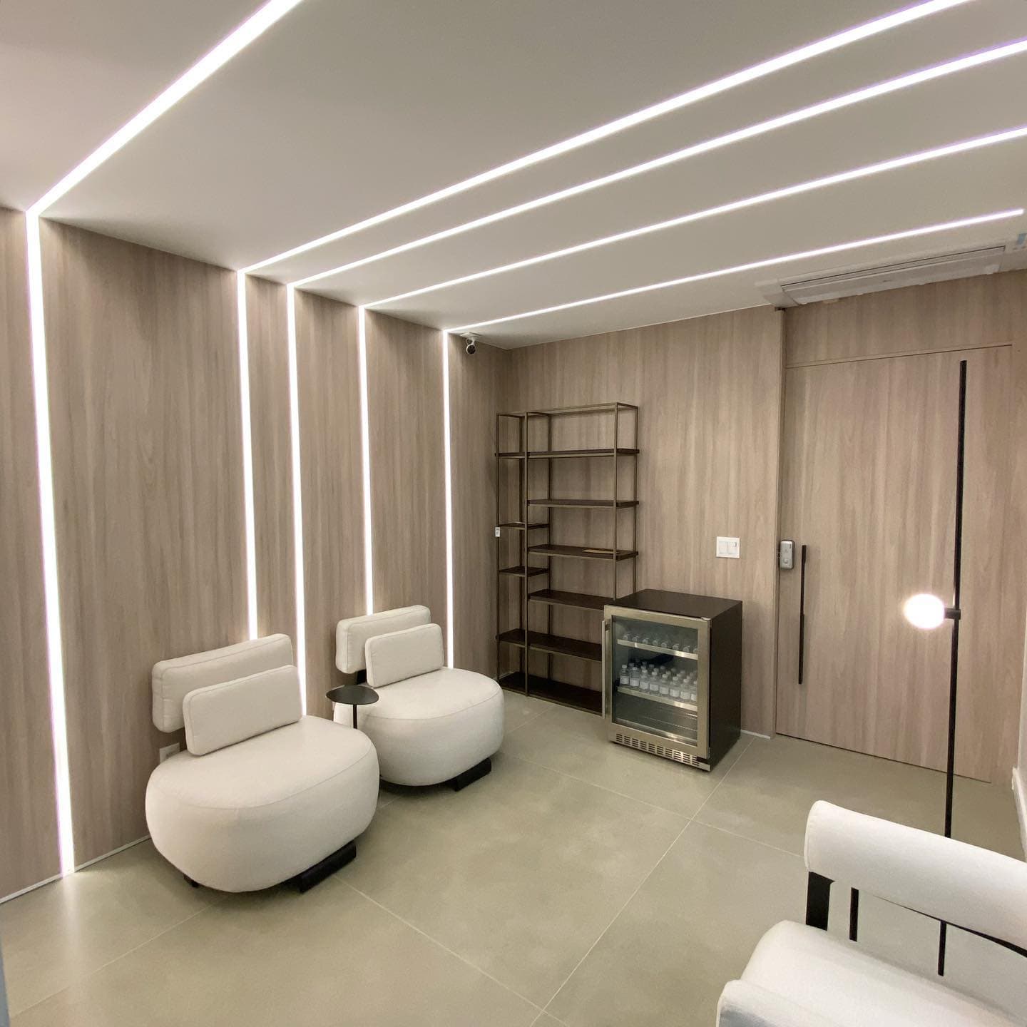 Lounge corporativo com paredes revestidas em madeira clara e iluminação linear embutida