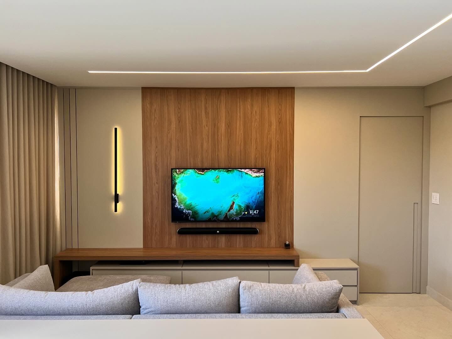 Sala de estar com painel de TV em madeira e rack planejado sob medida